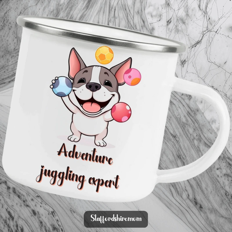 Funny Staffy bull terrier camping mug showing a happy dog juggling colorful balls, ideal for enjoying beverages outdoors.