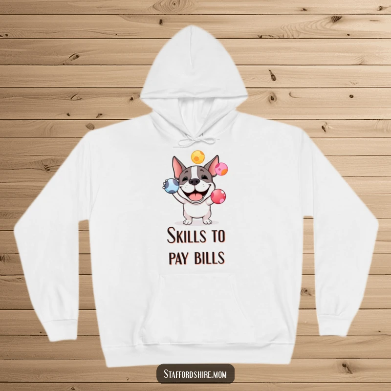 Funny Staffy bull terrier hoodie showing a happy dog attempting to juggle colorful balls, offering warmth and humor.