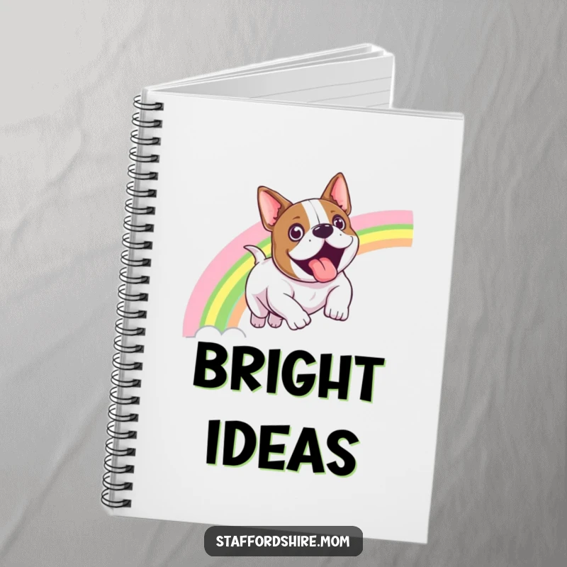 Funny Staffordshire bull terrier notebook showing a dog sliding down a bright rainbow with an expression of pure exhilaration.